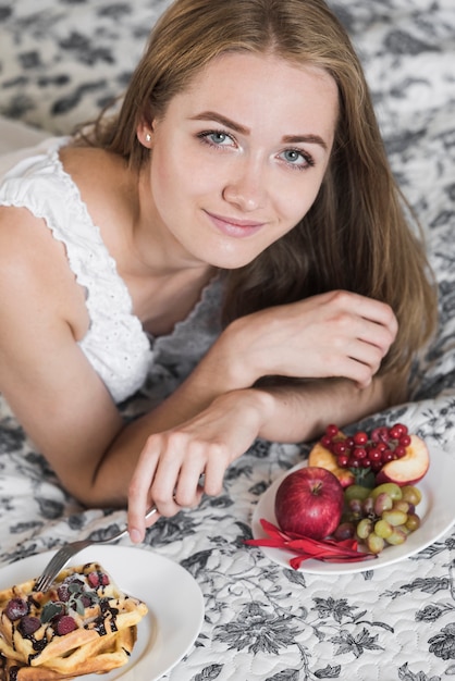 Free photo portrait of smiling young woman putting fork in the waffle