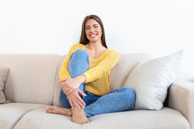 Portrait of a smiling young woman relaxing alone on her living room sofa at home in the afternoon