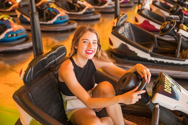 Portrait of smiling young woman sitting in the bumper car