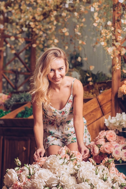 Free photo portrait of a smiling young woman standing behind the roses bouquet