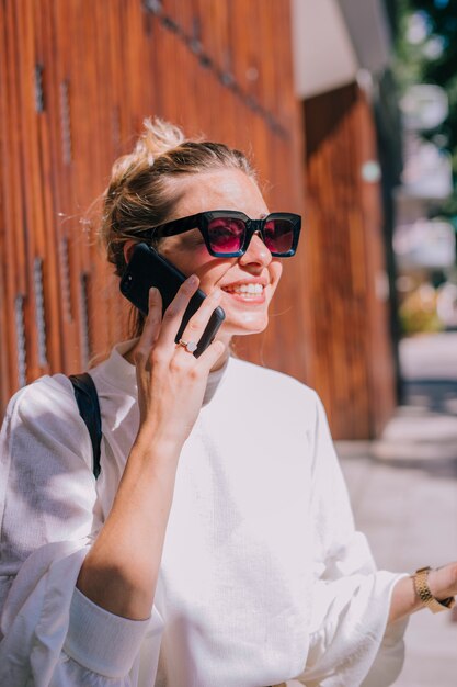 Portrait of a smiling young woman wearing sunglasses talking on cellphone