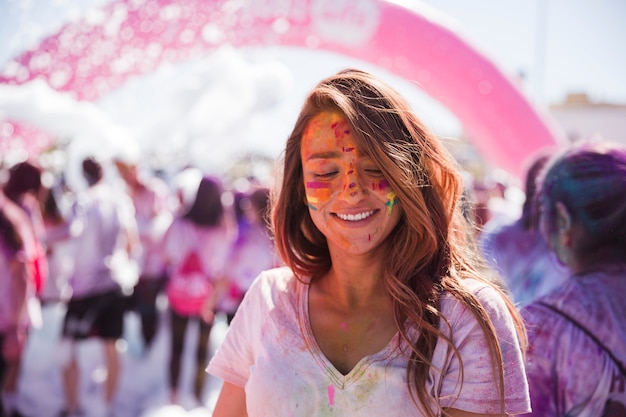 Portrait of a smiling young woman with holi color face