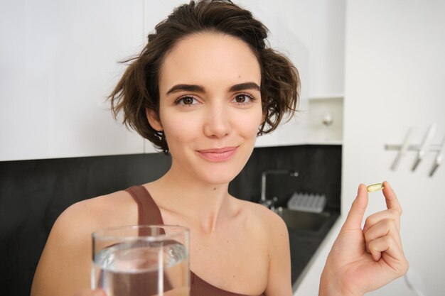 Portrait of sportswoman drinking water taking vitamins dietry supplements for healthy skin having