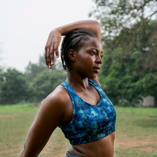 Portrait sporty woman in nature stretching