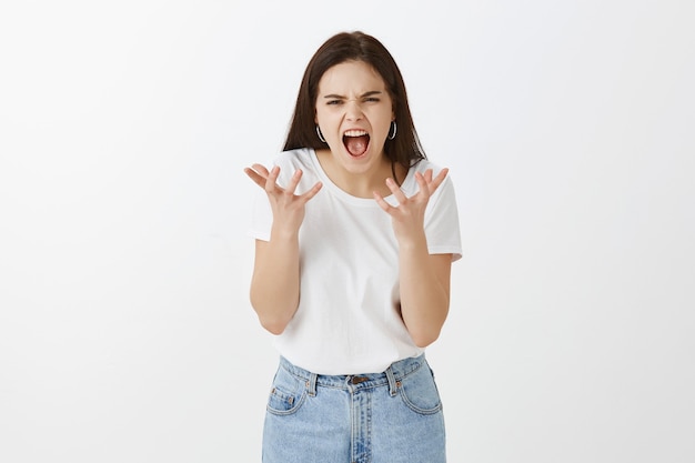 Portrait of stressed young woman posing against white wall