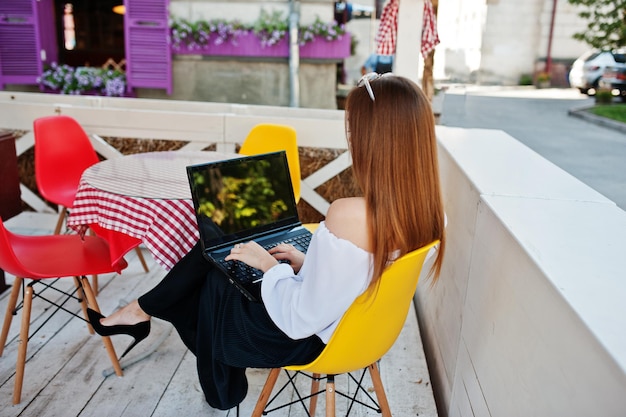 Free Photo portrait of a strong independent successful businesswoman wearing smart casual clothing and glasses working on a laptop in a cafe