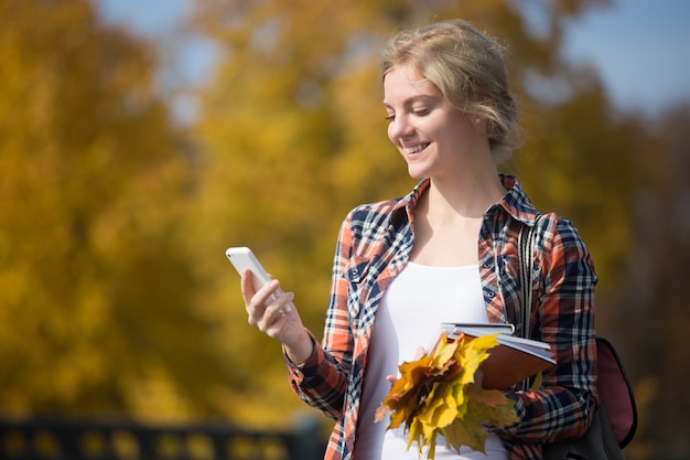 Portrait of student girl outsides, mobile phone in one hand