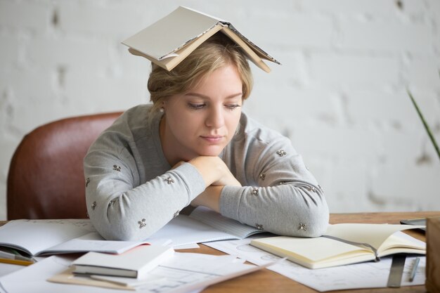 Portrait of student girl with open book on her head