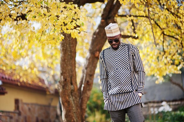 Portrait of stylish black african american man at hat and sunglasses against sunny autumn fall background Rich people in africa at traditional dress