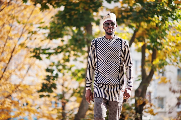 Portrait of stylish black african american man at hat and sunglasses against sunny autumn fall background