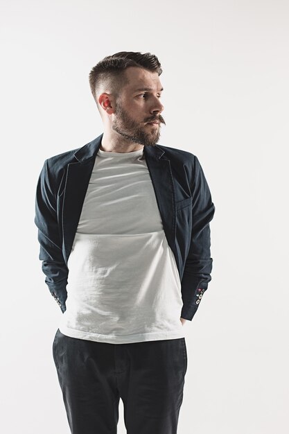 Portrait of stylish handsome young man standing at studio against white. Man wearing jacket