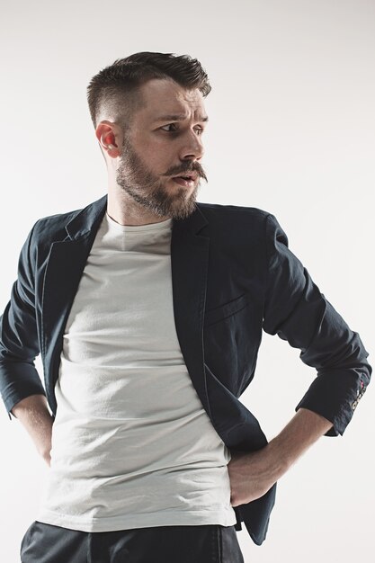 Portrait of stylish handsome young man standing at studio against white. Man wearing jacket