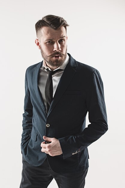 Portrait of stylish handsome young man standing at studio against white. Man wearing jacket