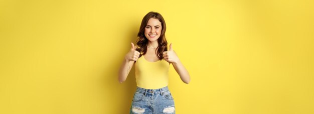 Portrait of stylish modern girl feminine woman showing thumbs up recommending gesture like or approv