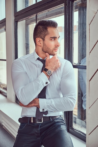 Free photo portrait of stylish muscular man sits near the window.