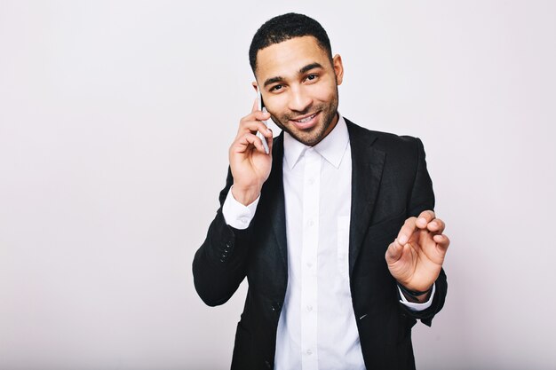 Portrait stylish young handsome man in white shirt, black jacket talking on phone and smiling. Achieve success, expressing true positive emotions, businessman.