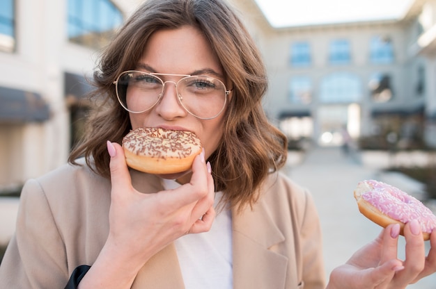 Free photo portrait of stylish young woman eating doughnuts