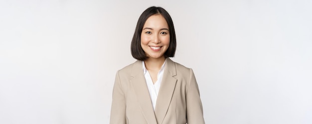 Portrait of successful businesswoman in suit smiling and looking like professional at camera white b