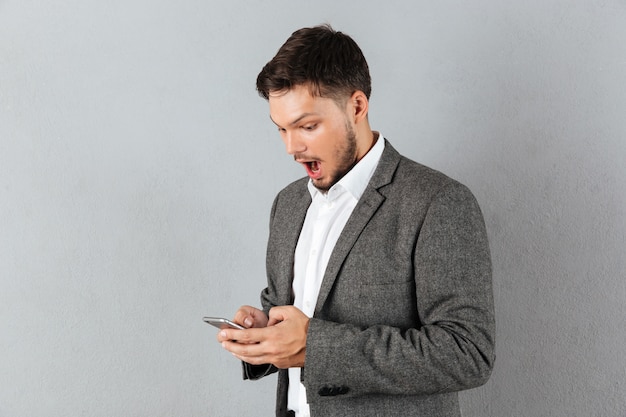 Portrait of a surprised businessman looking at mobile phone