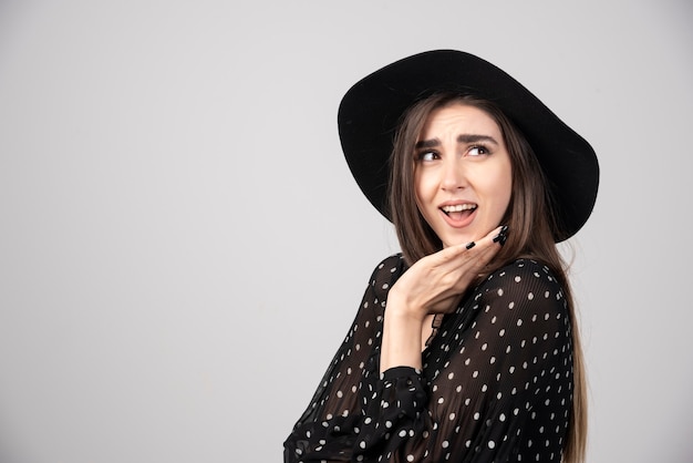 Portrait of surprised woman smiling on gray.