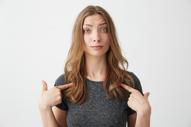 Free Photo portrait of surprised young beautiful girl pointing fingers at herself .