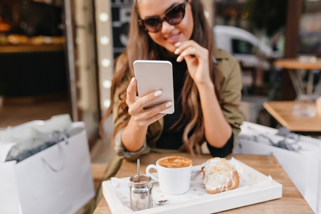 Free photo portrait of tanned lady with elegant manicure and cup of latte on foreground