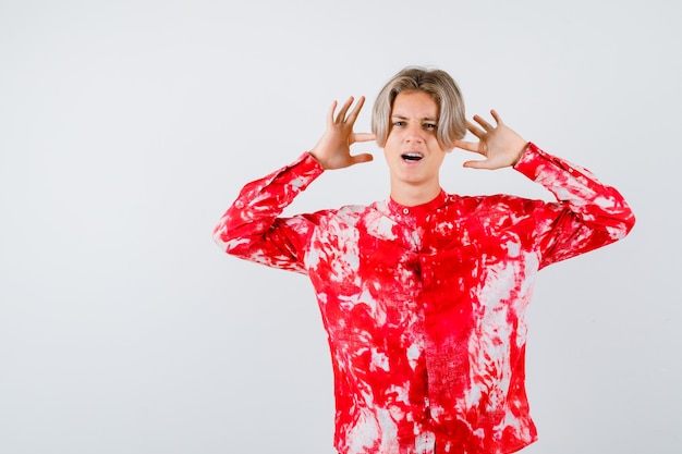 Free photo portrait of teen blonde male showing surrender gesture in oversized shirt and looking troubled front view