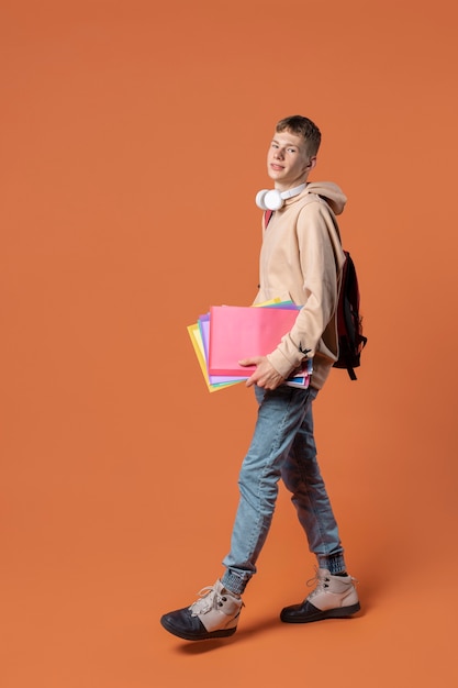 Free photo portrait of a teen boy holding his backpack and his folder