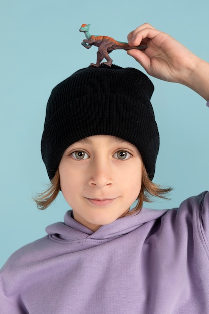 Portrait of teen boy keeping a dinosaur on his head