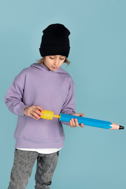 Portrait of teen boy playing with a big pencil