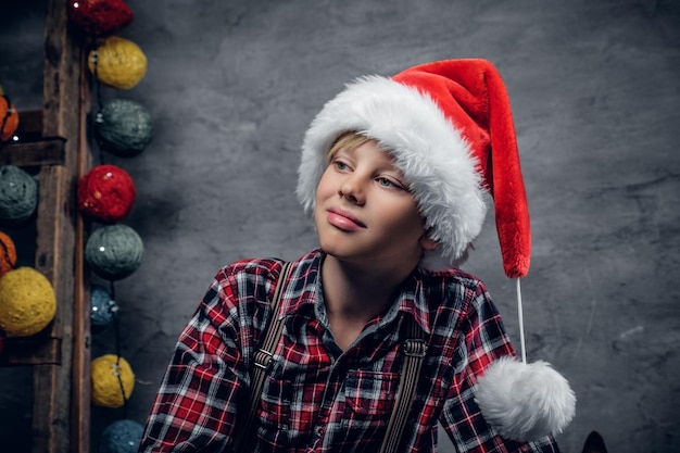 Free Photo portrait of teenage boy dressed in santa's hat and a plaid shirt.