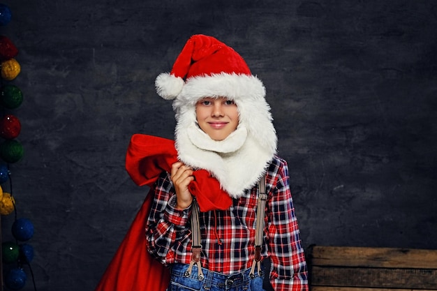 Free photo portrait of teenage boy dressed in santa's holiday costume and a plaid shirt.