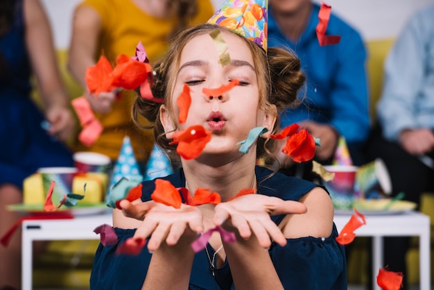 Free photo portrait of a teenage girl blowing confetti on her birthday