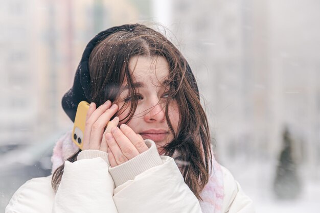 Free photo portrait of a teenage girl outdoors with a smartphone in snowy winter weather