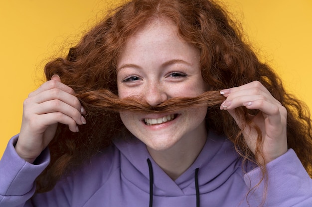 Free photo portrait of teenage girl showing a fake moustache