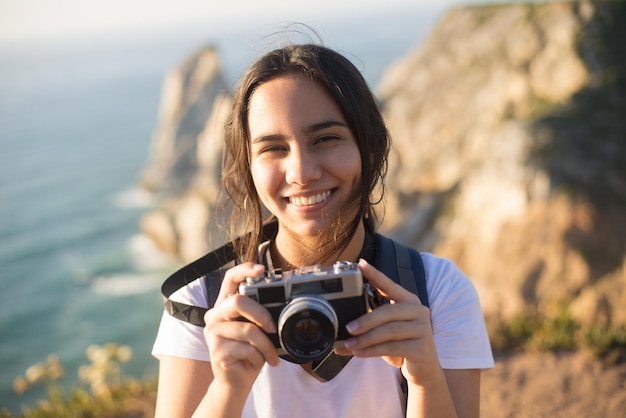 Free photo portrait of teenage girl with camera smiling