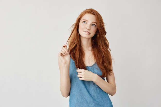 Free photo portrait of tender dreamy freckled ginger woman thinking, feeling insecure about her first date. growing up into gorgeous young woman. planning out on white. twenties concept.