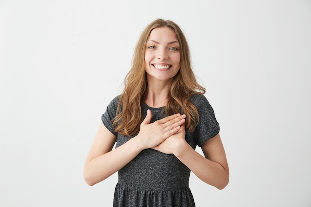 Portrait of tender happy young girl smiling holding hands on heart .