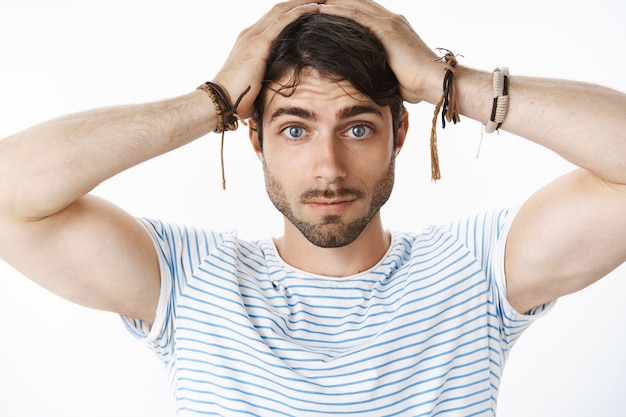 Free Photo portrait of tensed young attractive guy with blue eyes and beard feeling confused and unaware what do as being left alone with baby trying change diaper