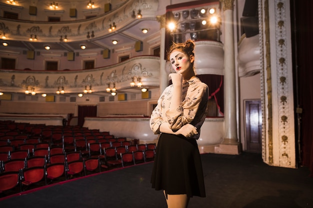 Free photo portrait of thoughtful female mime artist standing on stage