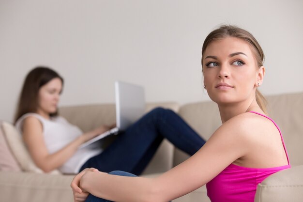 Portrait of thoughtful girl, girlfriend with laptop on backgroun