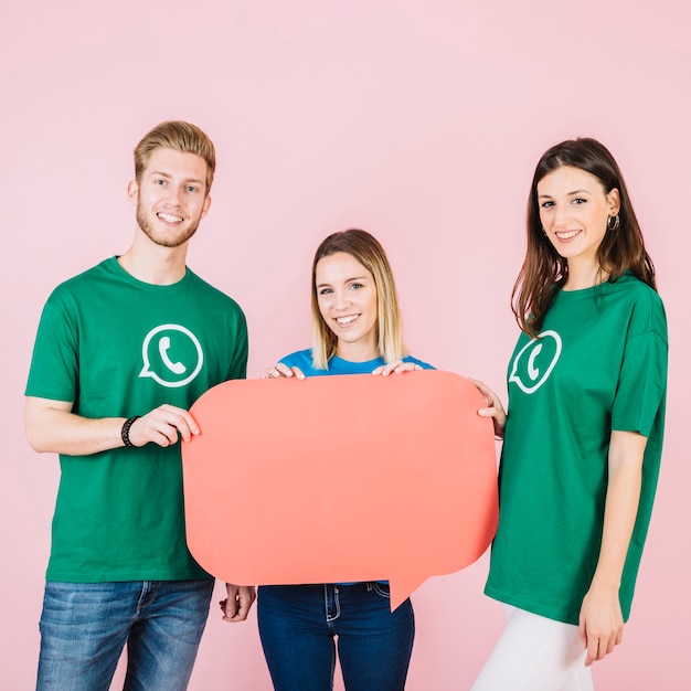 Free photo portrait of three happy friends holding empty green speech bubble