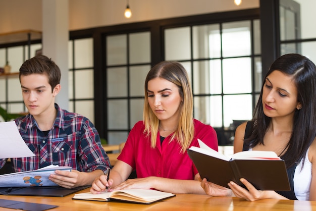 Free photo portrait of three serious students studying in library