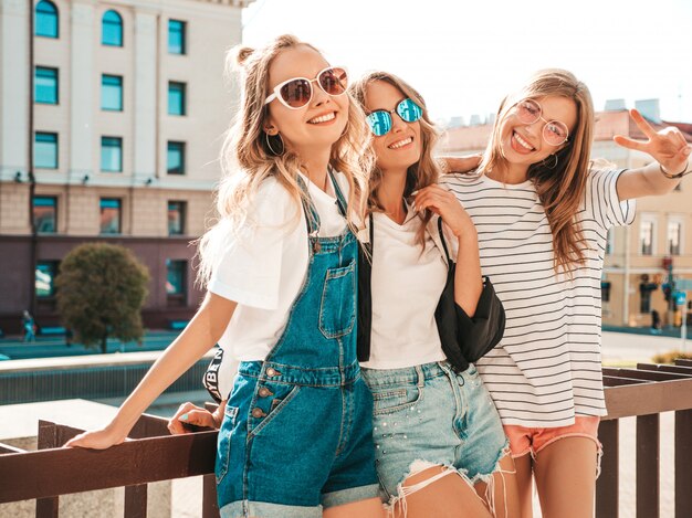 Portrait of three young beautiful smiling hipster girls in trendy summer clothes. Sexy carefree women posing on the street.Positive models having fun.Hugging