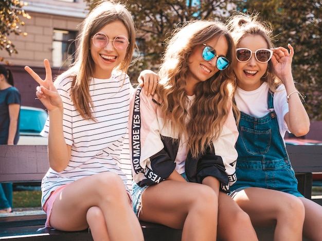 Free photo portrait of three young beautiful smiling hipster girls in trendy summer clothes. sexy carefree women posing on the street.positive models having fun in sunglasses.hugging