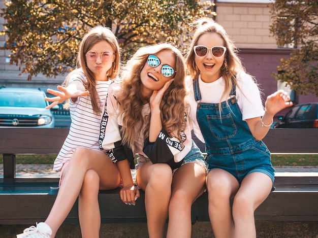 Free Photo portrait of three young beautiful smiling hipster girls in trendy summer clothes. sexy carefree women posing on the street.positive models having fun in sunglasses.hugging