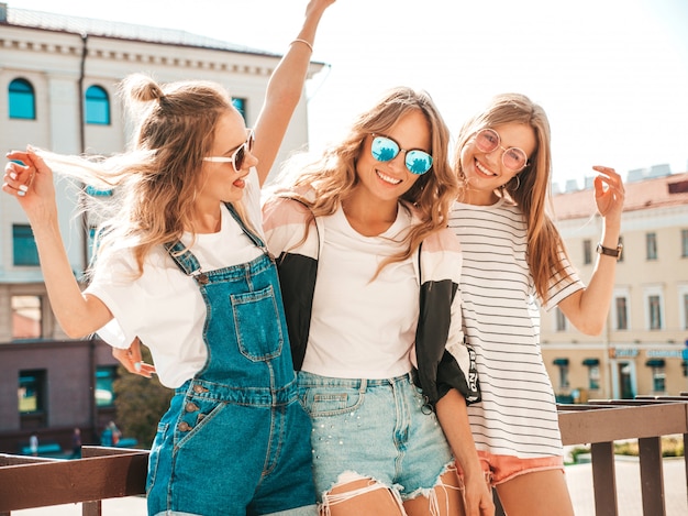 Free photo portrait of three young beautiful smiling hipster girls in trendy summer clothes. sexy carefree women posing on the street.positive models having fun in sunglasses.hugging