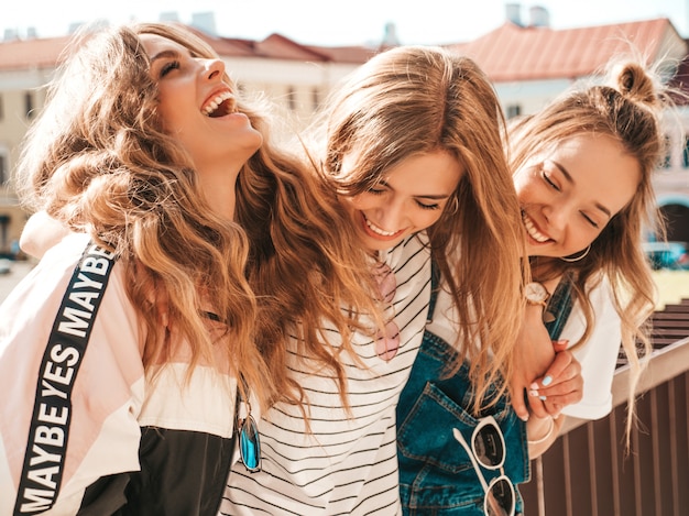 Portrait of three young beautiful smiling hipster girls in trendy summer clothes. Sexy carefree women posing on the street.Positive models having fun