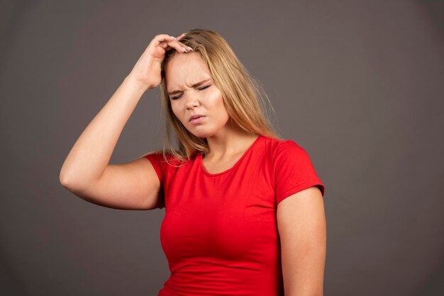 Portrait of tired woman touching her head over dark background. High quality photo