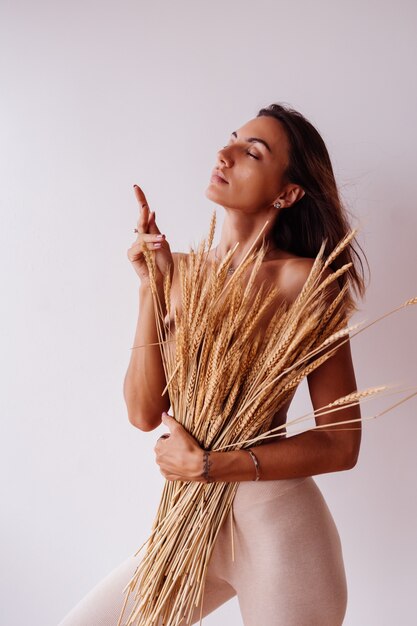 Portrait of topless woman in fitting leggings holding wild dried flowers